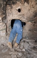 Dr. Steve Nash crawls through a door at the Hinkle Park Cliff dwelling research site.