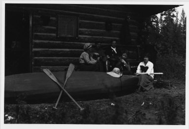 Unidentified people outside log cabin