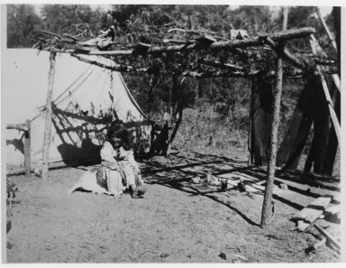 Camp scene showing tent with adjacent ramada.