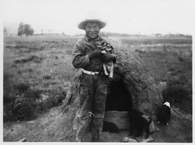 Oliver Levato holding a puppy in front of an earth oven.