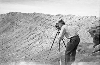 Alfred M. Bailey with movie camera on crater rim