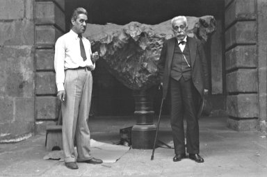 2 men posing with Meteorite on pedestal