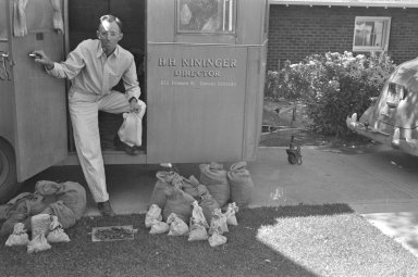 H.H. Nininger in American Meteorite Laboratory with specimen bags in what apears to be the driveway of his house