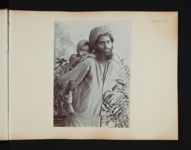 Bearded man in turban with a child on his back in Simla, India.