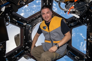 Kjell Lindgren sitting in front of the International Space Station