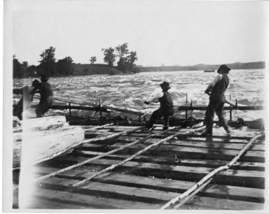 Men manuvering a log raft