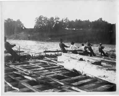Men manuvering a log raft